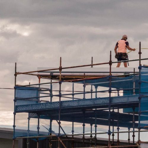 Construction worker on top of building against the sky, with scaffolding